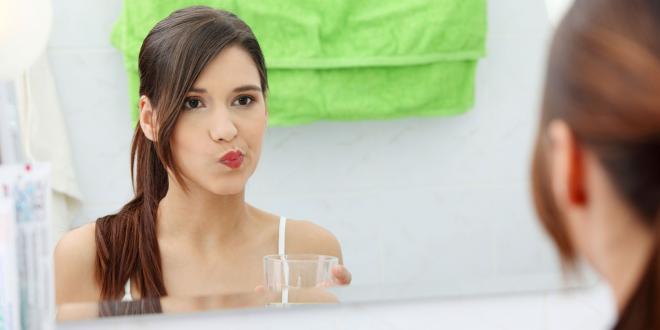 Oil Pulling girl in bathroom rinsing mouth