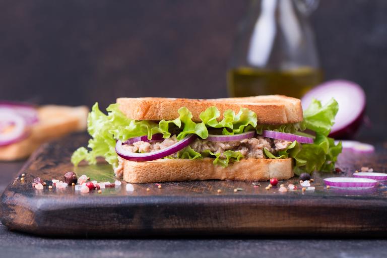 a tuna salad sandwich with red onion and lettuce
